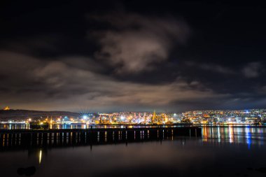 Gece Murmansk, körfeze yansıyan şehir ışıkları ve limanda duran gemiler.