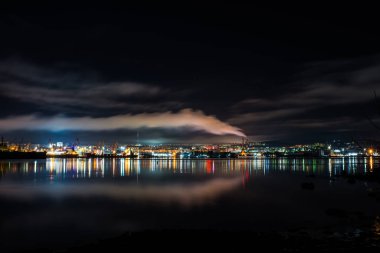 Gece Murmansk, körfeze yansıyan şehir ışıkları ve limanda duran gemiler.
