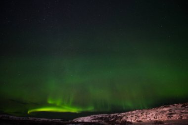 Tepeler, berrak yıldızlı gökyüzü ve renkli kuzey ışıkları, inanılmaz bir doğa olayı.
