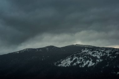 Büyük, gri bulutlar Taganay Ulusal Parkı 'nın sıradağları üzerinde kış sabahının erken saatlerinde gökyüzünde yavaşça süzülür.