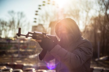 Stalker 'da kostüm, maskeli bir adam elinde makineli tüfekle duruyor.