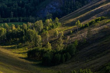 Bir yaz akşamında, batan güneşin altında küçük, alçak dağlar.