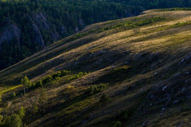 Bir yaz akşamında, batan güneşin altında küçük, alçak dağlar.