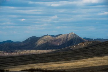 Bulutlar gökyüzünde süzülür, dağlarda bir ışık gölgesi deseni oluşturur.