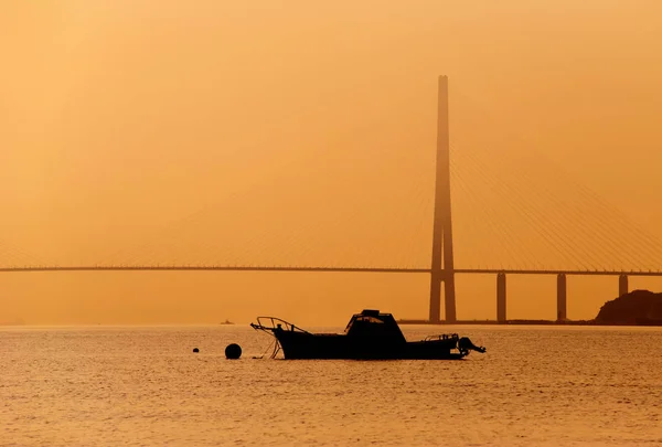 Boot auf einer Straße im Meer gegen eine Brücke, Sonnenuntergang — Stockfoto