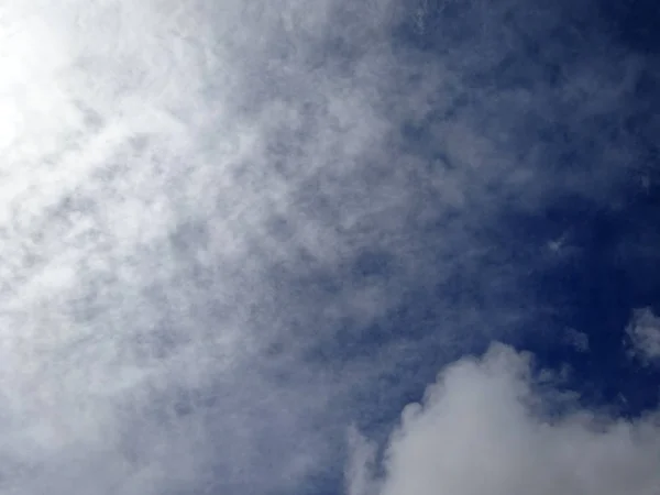 Nubes esponjosas lanzan en un cielo azul — Foto de Stock