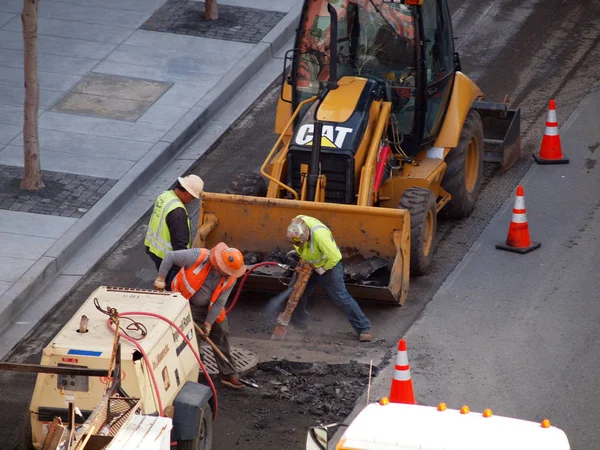 Lavoratori edili scavare strada con l'aiuto di macchine — Foto Stock
