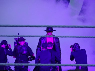 WWE güreşçi şapkasını ve paltosunu giyiyor Undertaker t doğru yürür.