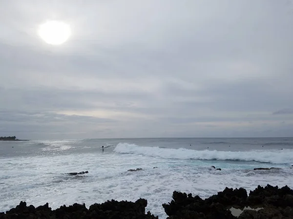 Волны катятся к берегу с людьми, занимающимися серфингом — стоковое фото
