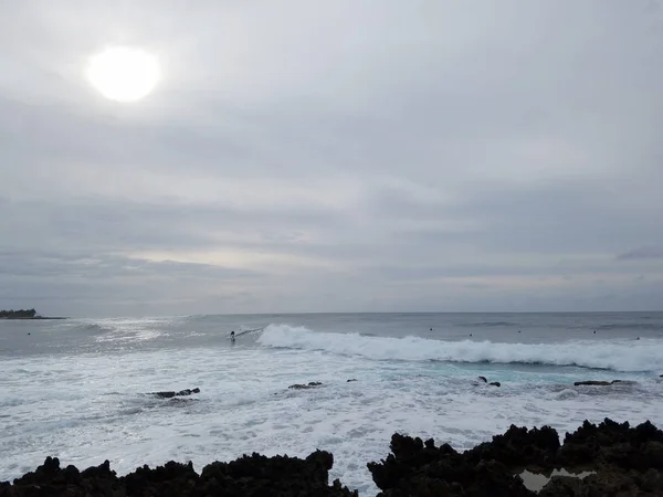 Ondas rolam em terra com pessoas surfando — Fotografia de Stock