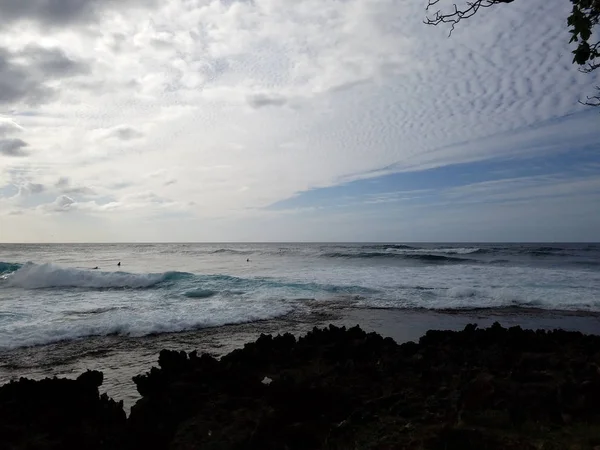 Волны катятся к берегу с облаками в небе — стоковое фото