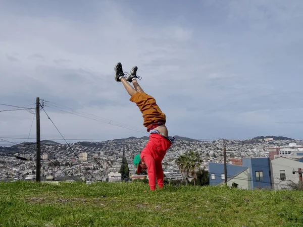 Mann macht Handstand auf Hügel vor Gebäuden — Stockfoto