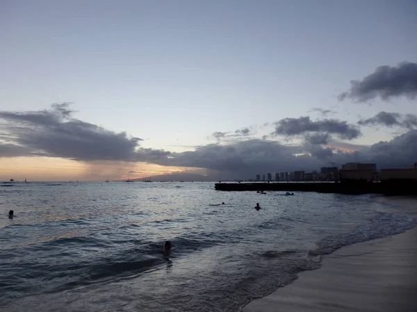 Les gens jouent dans l'eau au crépuscule sur la plage de San Souci — Photo