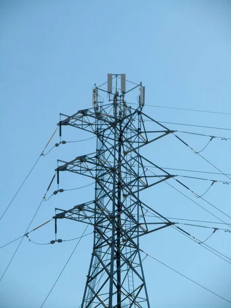 高圧送電線と交わるセルタワー青い空を背景に大規模な金属電柱 — ストック写真