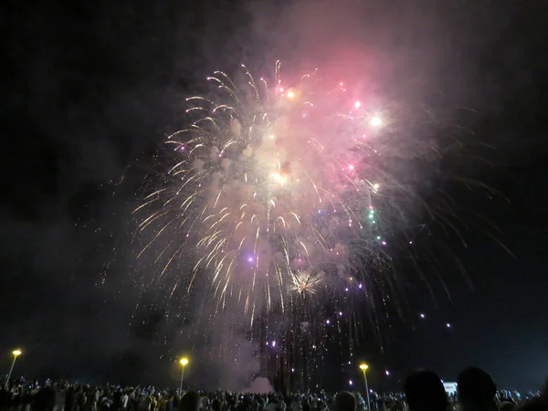 Los fuegos artificiales de Año Nuevo estallaron en el aire mientras la gente mira la exhibición en —  Fotos de Stock