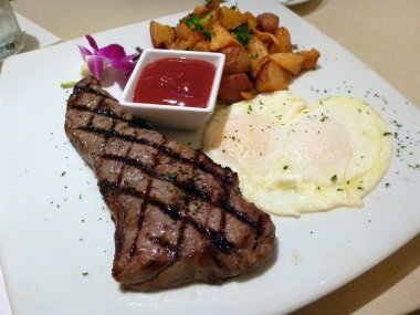 İki yumurtalı biftek, patates ve bir fincan ketçap. 