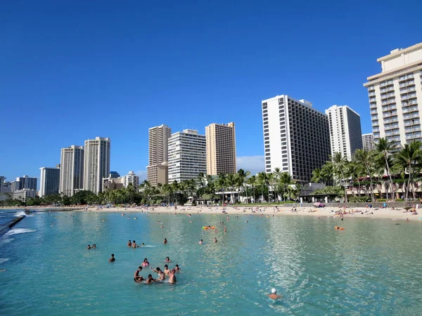 People play in the protected water and hang out on the beach in — Stock Photo, Image