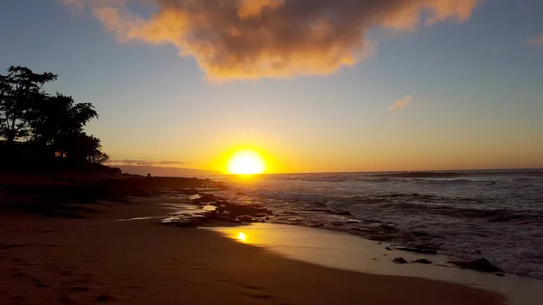 Puesta de sol sobre el océano con olas moviéndose a la orilla —  Fotos de Stock