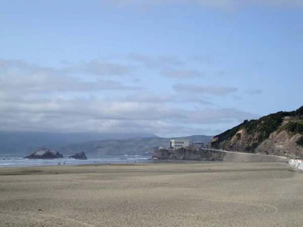 オーシャンビーチは 晴れた日にサンフランシスコの崖の家に向かっています 人口が少なく 山にタイヤトラックが見えます — ストック写真