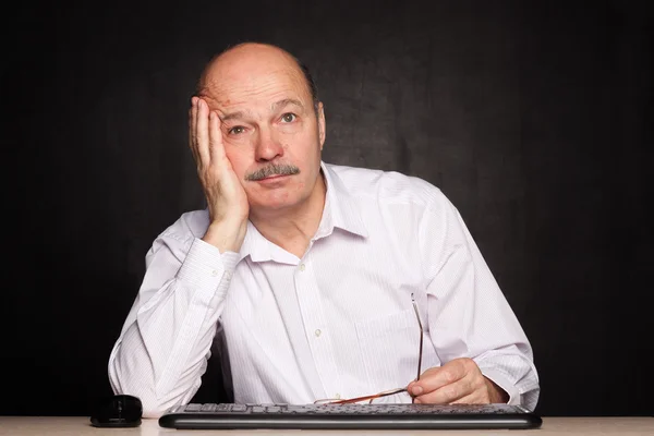 Elderly man at work dreamily looks away during a break. — Stock Photo, Image