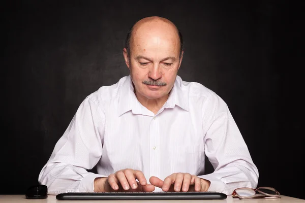 Homem em uma camisa branca trabalha no computador, digitando texto no teclado — Fotografia de Stock