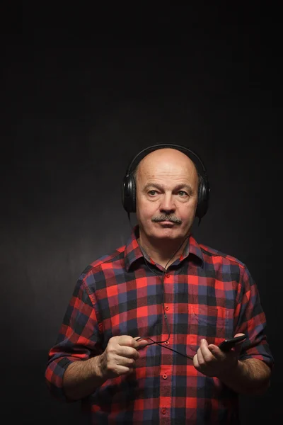 Homem idoso com fones de ouvido ouvindo música com desagrado . — Fotografia de Stock