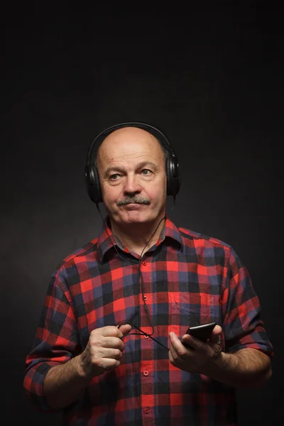 Homem idoso com fones de ouvido ouvindo música com desagrado . — Fotografia de Stock