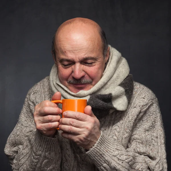 Homem idoso em um lenço de lã bebendo remédio frio . — Fotografia de Stock