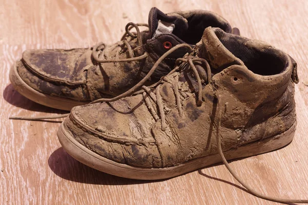 Zapatos sucios con barro seco en el suelo — Foto de Stock