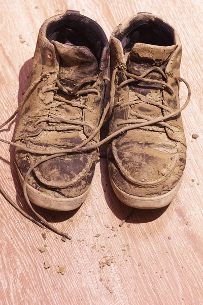 Βρώμικα παπούτσια με αποξηραμένη λάσπη στο πάτωμα — Φωτογραφία Αρχείου