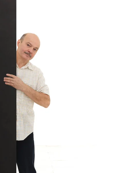 Homem idoso olha para fora por trás da parede preta — Fotografia de Stock