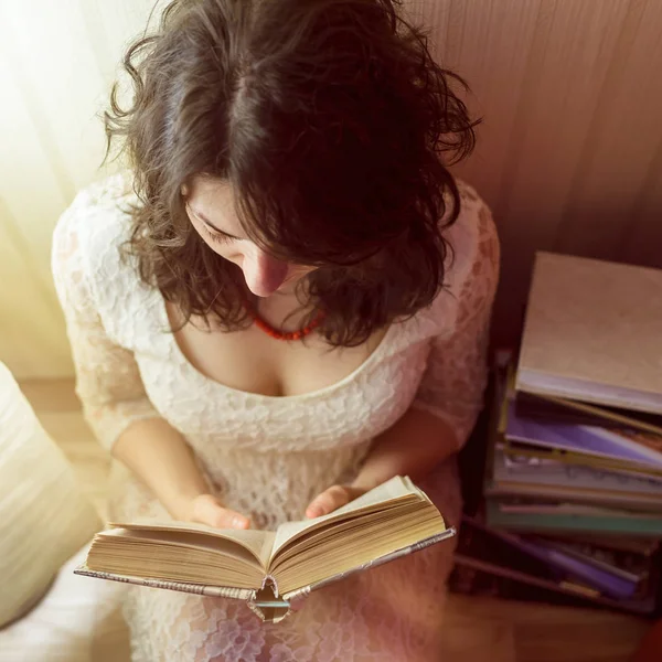 Meisje leest een boek bij het licht van de lamp. Uitzicht vanaf de top naar beneden — Stockfoto