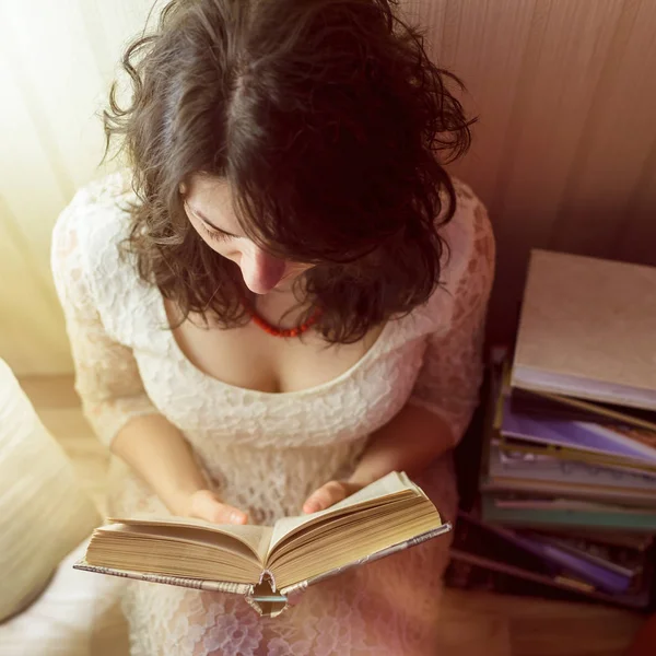 Tjej läser en bok av ljuset från lampan. Utsikt från toppen ner — Stockfoto