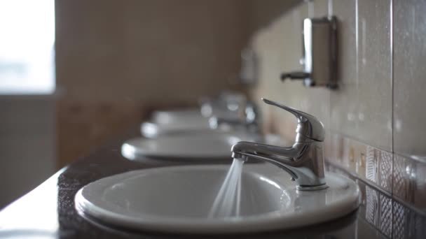 Vatten rinner ur kranen på en offentlig toalett. Ingen här. Avfall och orimlig användning. — Stockvideo