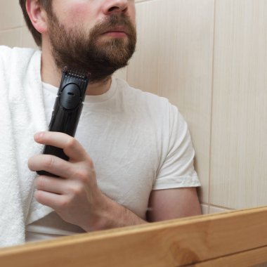 Sakallı, sakallı, sakalını tıraş eden genç bir adam..