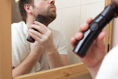 Sakallı, sakallı, sakalını tıraş eden genç bir adam..