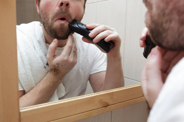 Jongeman met een baard scheermesje met elektrisch scheermes. — Stockfoto