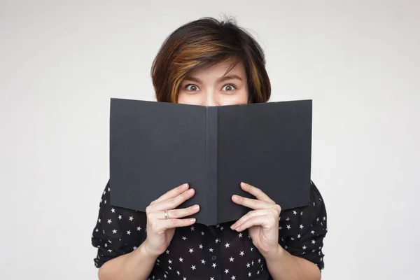 Mädchen bedeckt ihr Gesicht mit Buch — Stockfoto