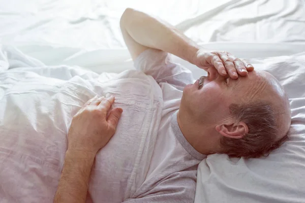 Hombre se encuentra en una cama en el dormitorio — Foto de Stock