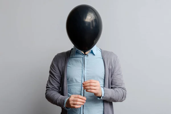 En hvit mann dekker ansiktet sitt med en svart ballong – stockfoto