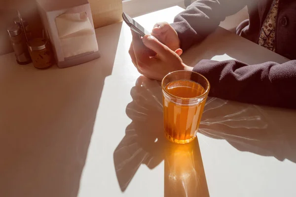 Ein Mädchen sitzt in einem Café und schaut in das Telefon — Stockfoto