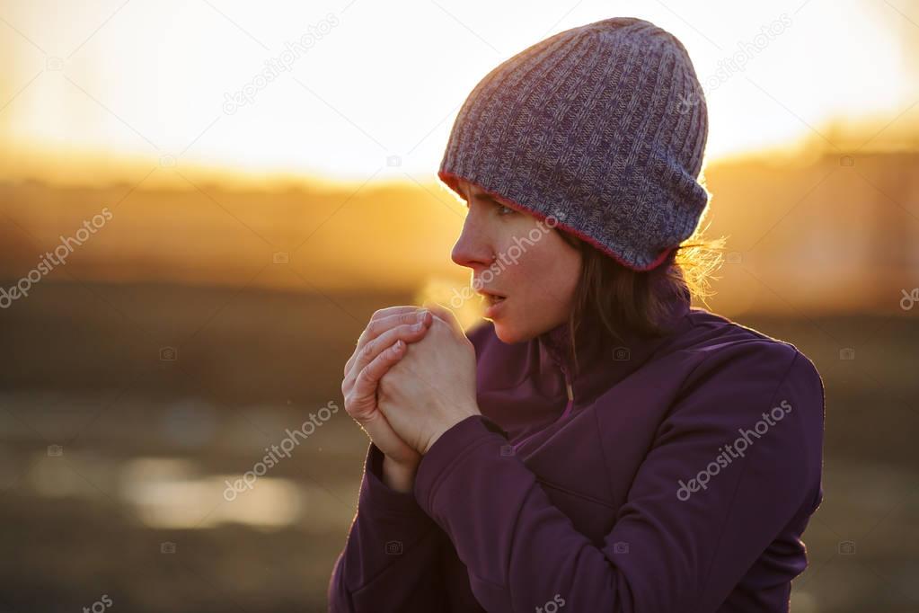 A girl in sports clothes breathes in the palm of her hand trying