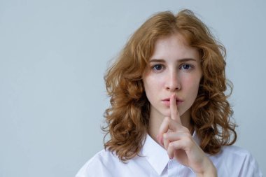 Çilli kızıl saçlı, kıvırcık saçlı bir kızla parmağını dudaklarına için koyar..