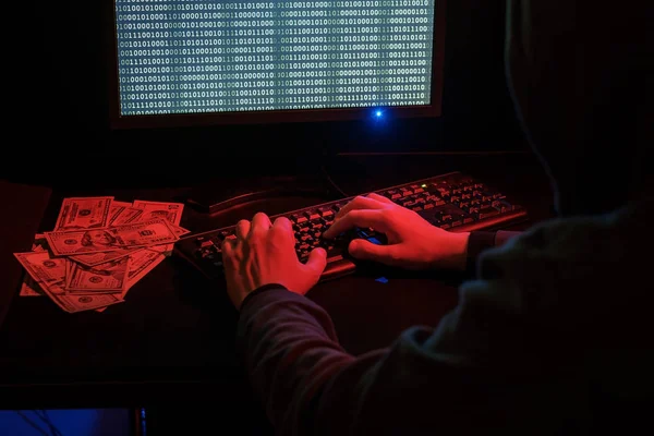 The man in the hood checks the malicious code on the keyboard. — Stock Photo, Image