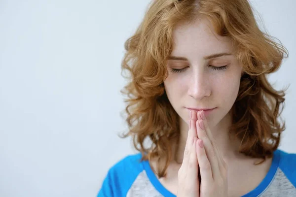 Una chica pelirroja con rizos dobló sus manos en oración —  Fotos de Stock