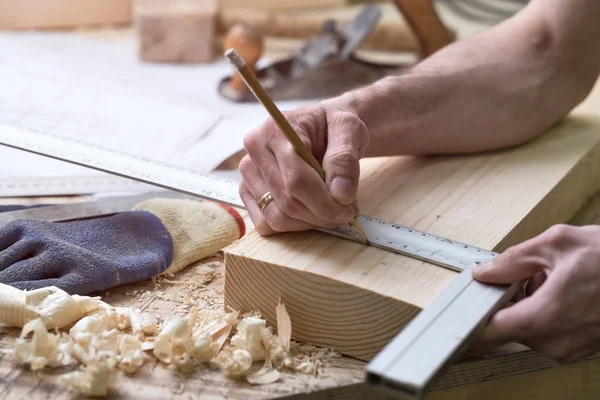 O carpinteiro faz marcas com um lápis em uma tira de madeira . — Fotografia de Stock