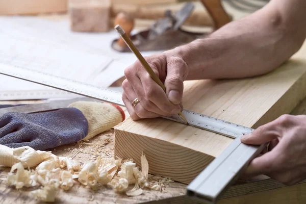 Der Tischler zeichnet mit dem Bleistift auf einem Holzstreifen. — Stockfoto