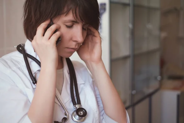 A young tired doctor talks on the phone after a difficult day.