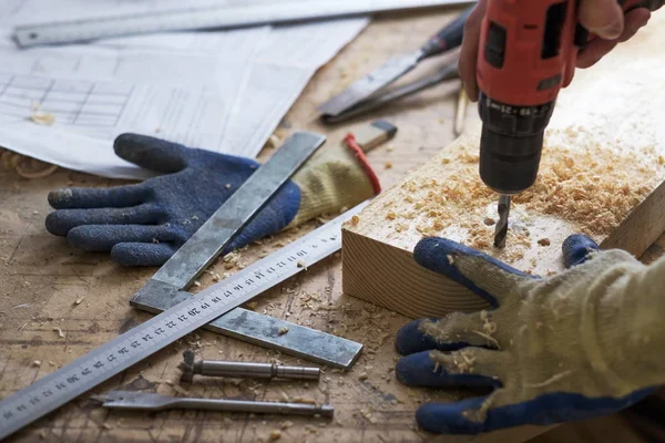 El carpintero hace agujeros con un taladro en una parte de madera — Foto de Stock