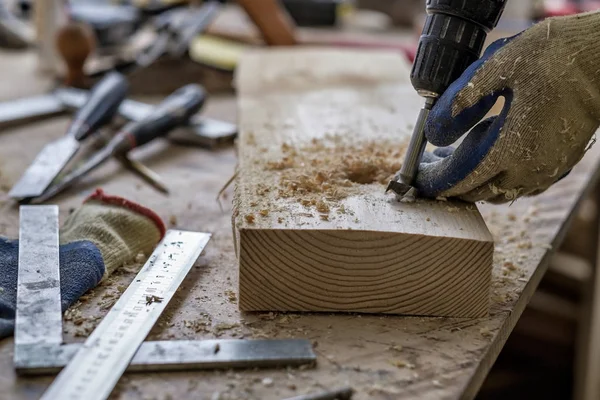 Der Tischler macht Löcher mit dem Bohrer in das Holzteil — Stockfoto